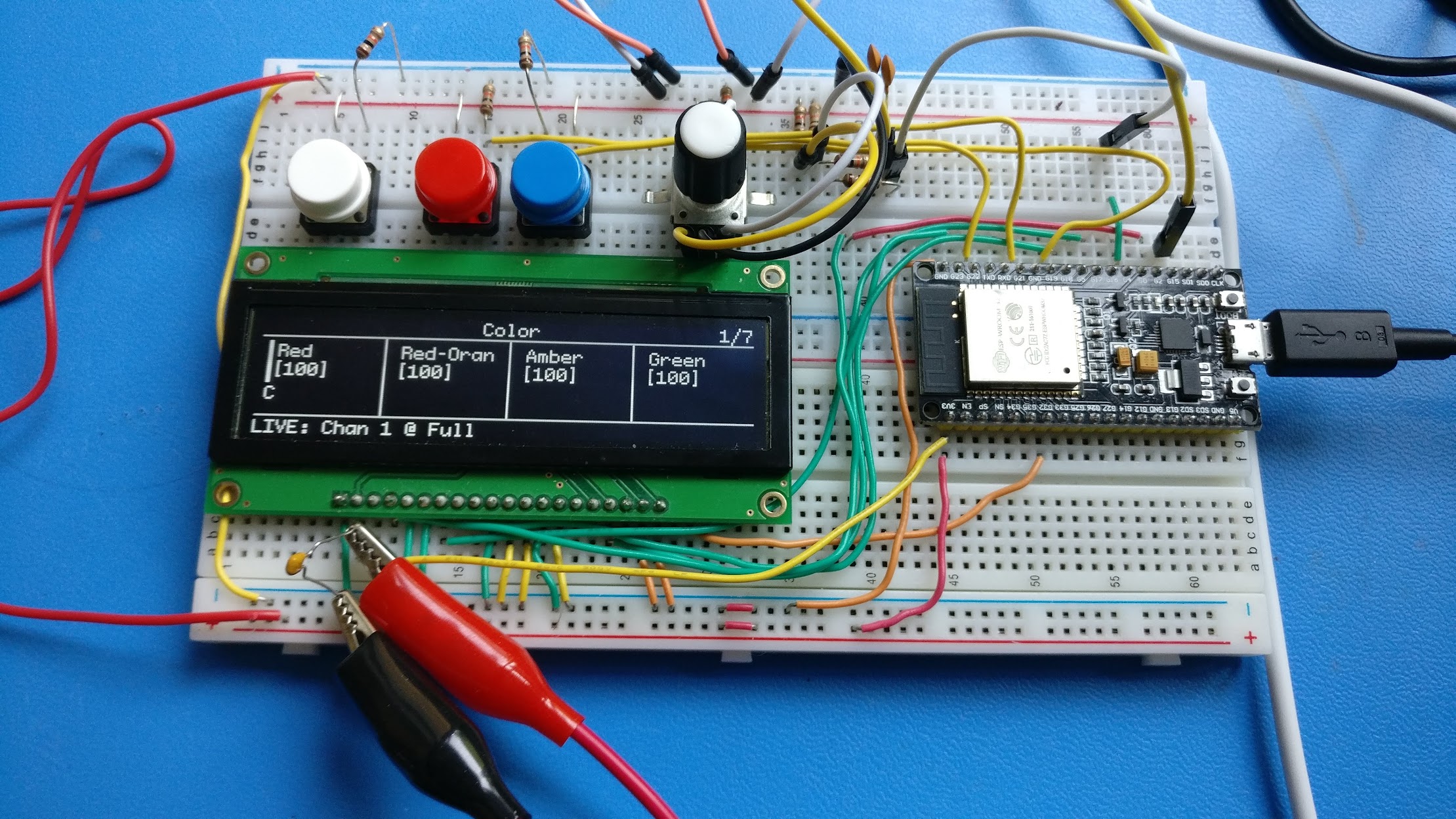 An electronics prototyping breadboard with four encoders, and a big monochrome OLED display wired to a microcontroller.