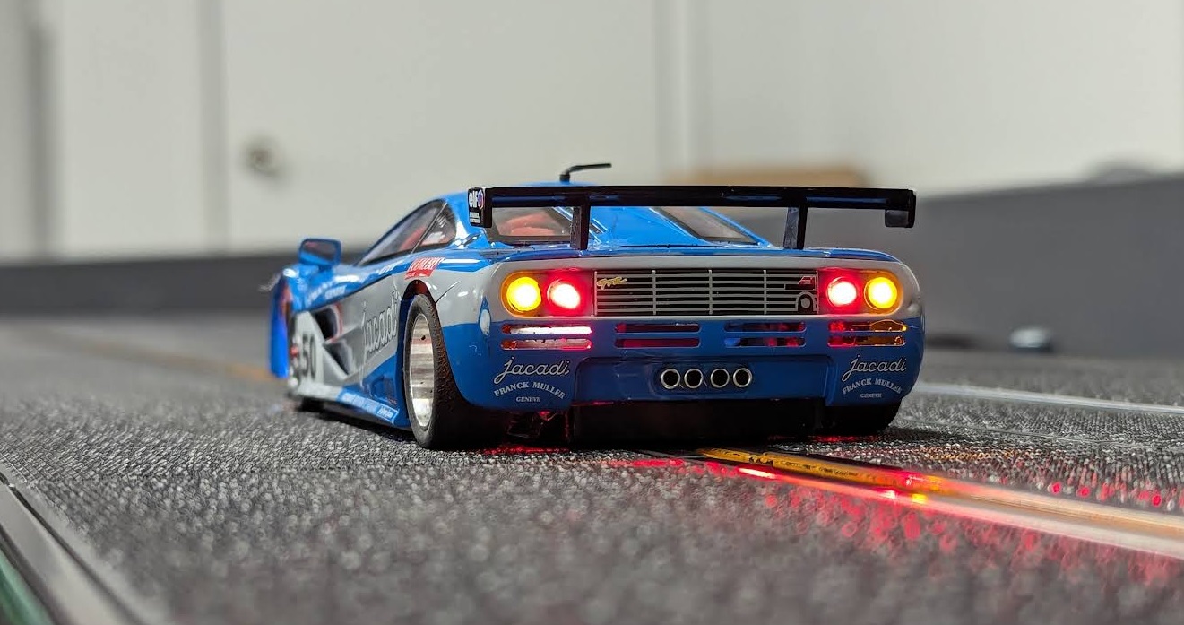 Back view of a racing slot car with the taillights and hazard lights on