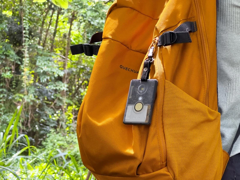 A photo of an orange backpack with a credit card shaped circuit board clipped to it