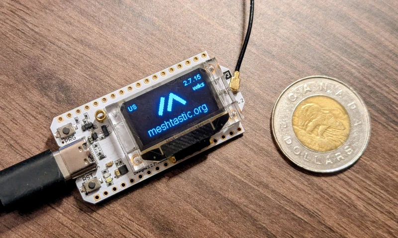 A Heltec V3 board  with a the meshtastic logo, and a toonie for scale