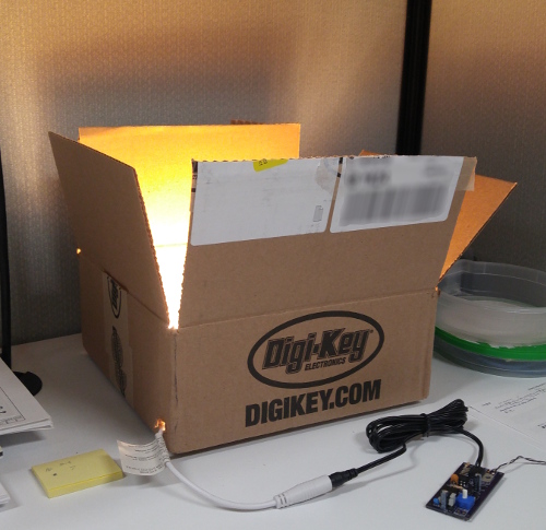 Image of the PWM Controller driving an LED strip, making the inside of a digikey box glow
